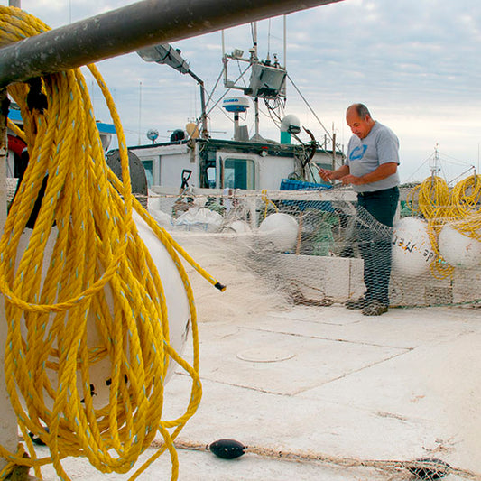 A Canadian fisherman repairs his nets at the end of his overnight workday in New Brunswick, Canada