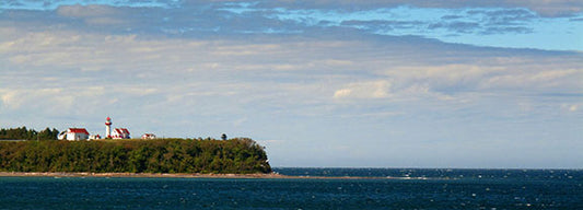 A lighthouse stands on duty on the banks of the Saint Lawrence River in Quebec, Canada.