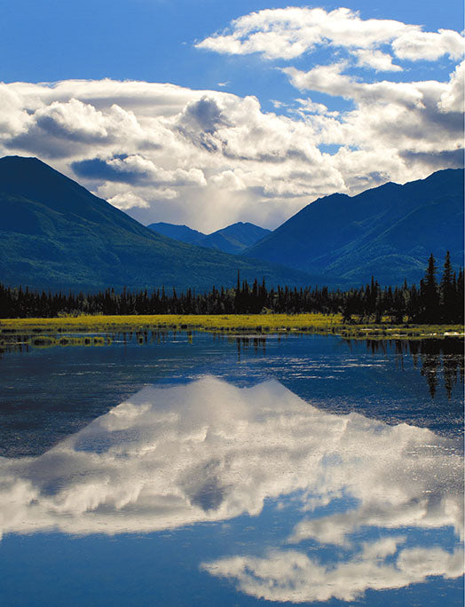 Mountains are reflected in the mirror-like surface of a still lake in Canada.