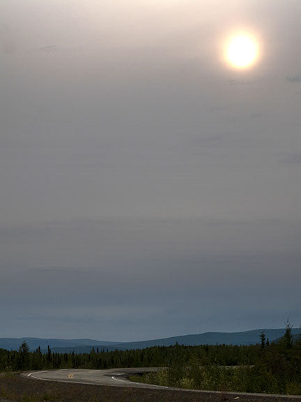The sun burns its way through the clouds over a bend in the Haul Road (a.k.a. the Dalton Highway) in Alaska